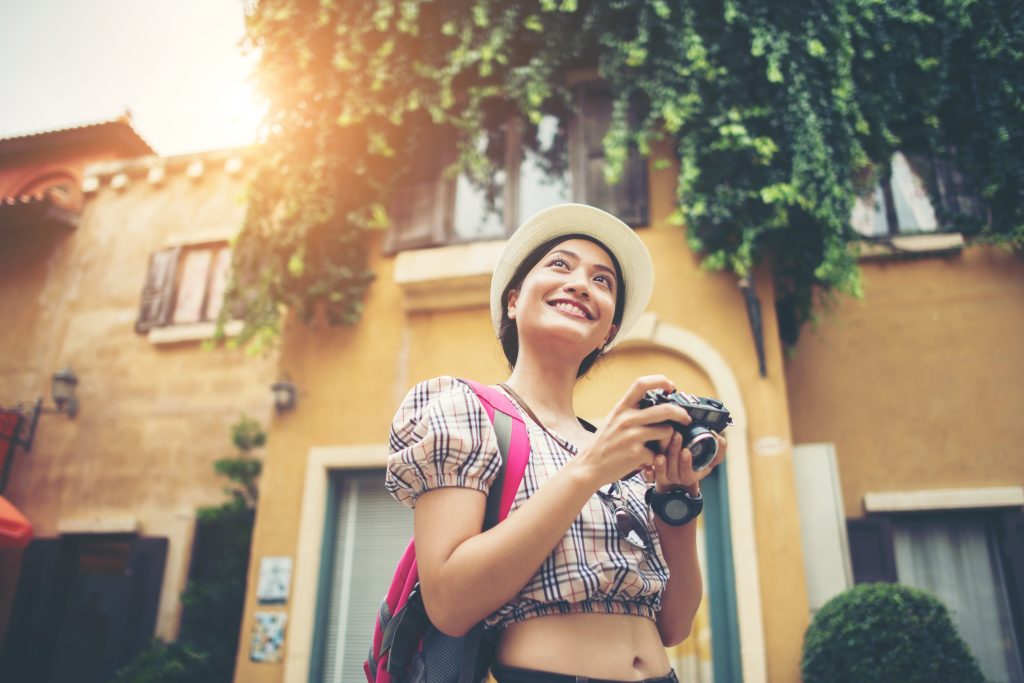 Portrait of young hipster woman backpack traveling taking photo